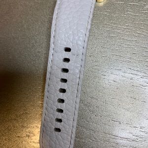 White leather belt with gold dial.